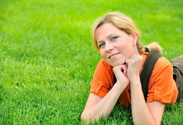 Ung kvinna avkopplande på gräset — Stockfoto