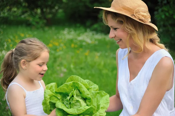 Young mother and daughter with lettuce — Stock Photo, Image