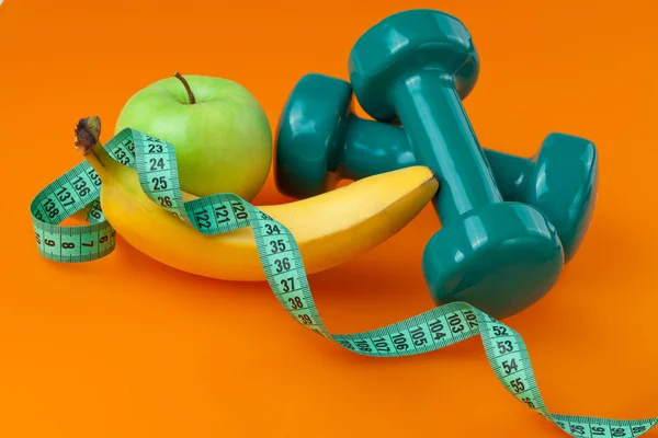 Dumbells with measuring tape and fruits — Stock Photo, Image