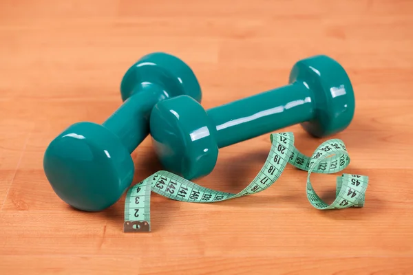 Green dumbells with measuring tape — Stock Photo, Image