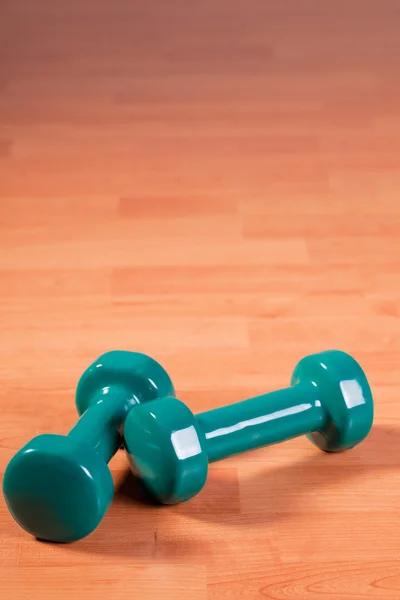 Green dumbells on wooden background — Stock Photo, Image