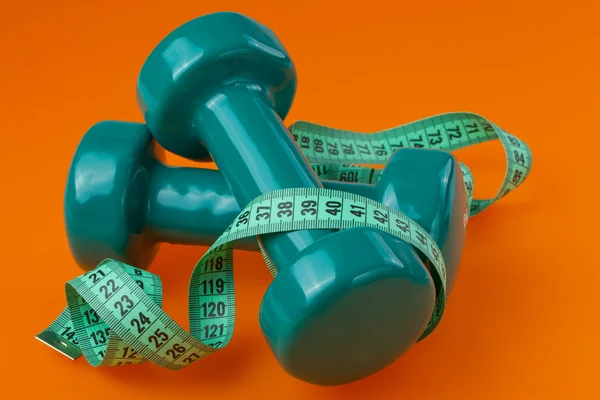 Two dumbells with measuring tape — Stock Photo, Image