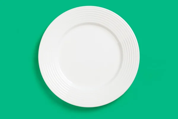 Белая тарелка на зеленом фоне — стоковое фото