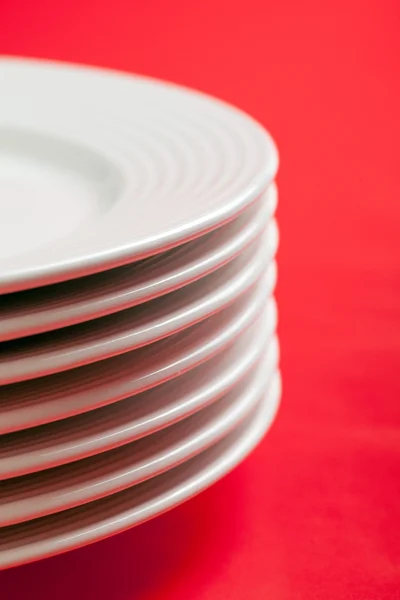 Белая тарелка на красном фоне — стоковое фото