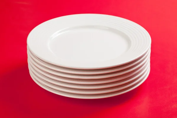 Белая тарелка на красном фоне — стоковое фото