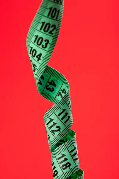 Fita de medição em fundo vermelho — Fotografia de Stock