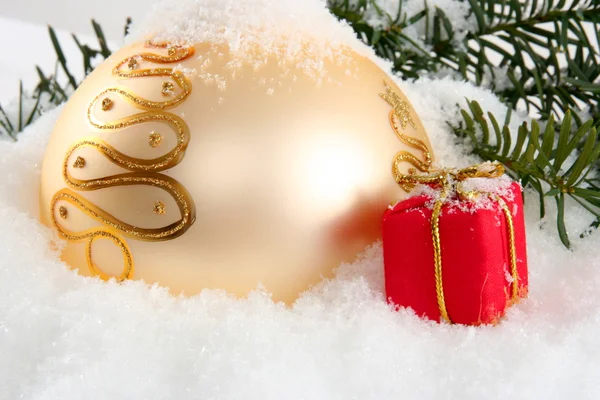 Goldene Christbaumkugel mit rotem Geschenk — Stockfoto
