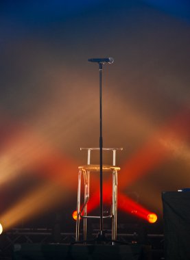Microphone and chair in lights on stage clipart