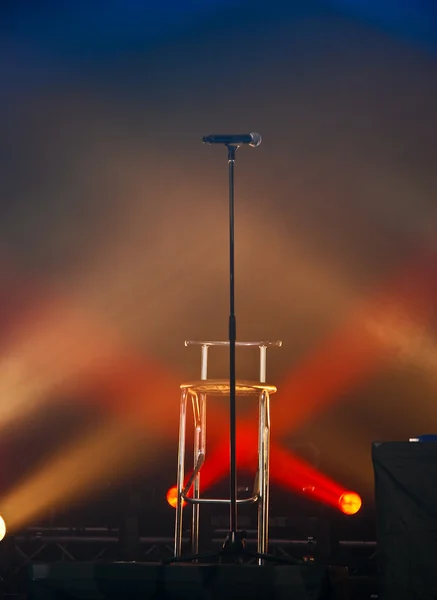 Микрофон и стул в свете на сцене — стоковое фото