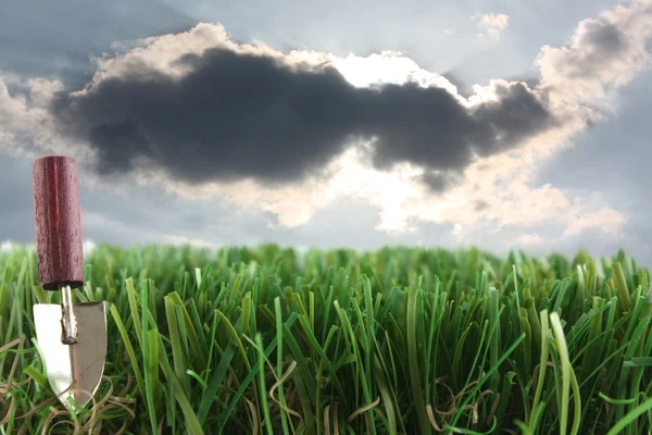 Трава и лопата с грозовыми облаками — стоковое фото