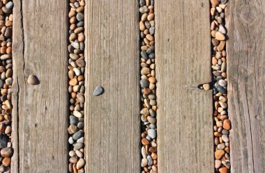 Stones in deckings gaps on beach clipart