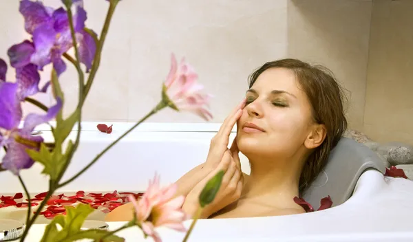 Kvinna i ett bad med rosenblad — Stockfoto