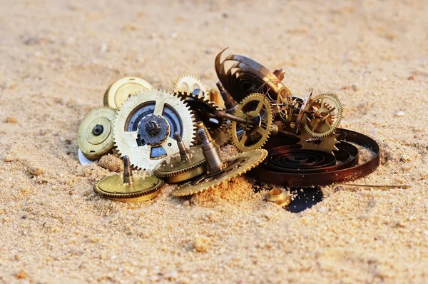 Části mechanismu hodinky na písku — Stock fotografie