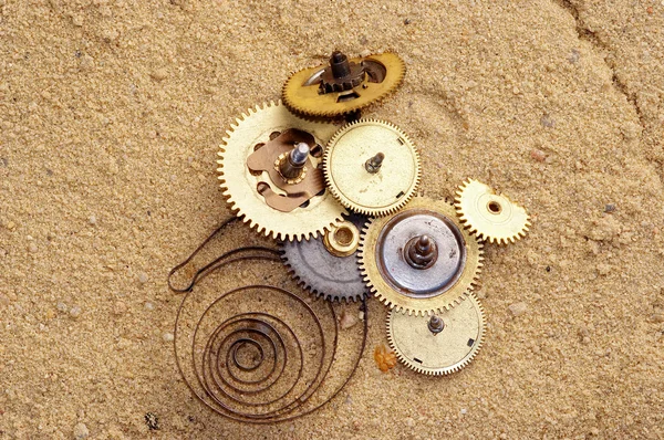 Parts of clockwork mechanism on the sand — Stock Photo, Image