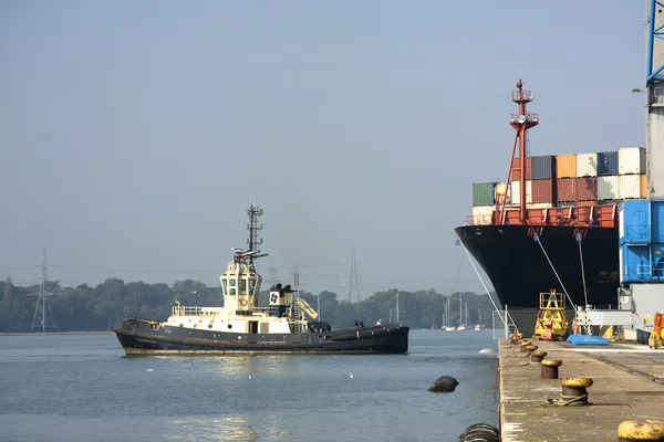 Контейнерний корабель і буксирний човен — стокове фото