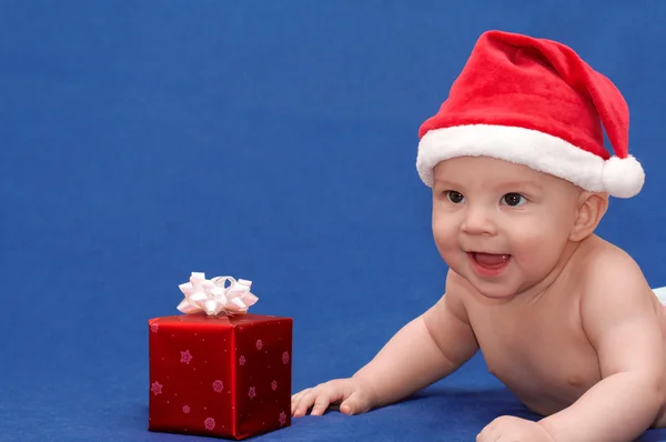 Baby in santa's cap met cadeau — Stockfoto