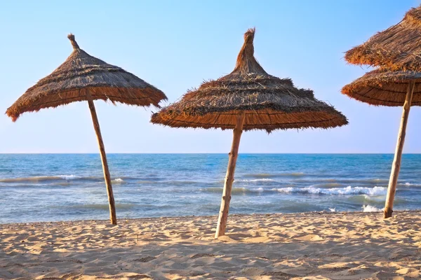 Halmtak parasoll på stranden — Stockfoto