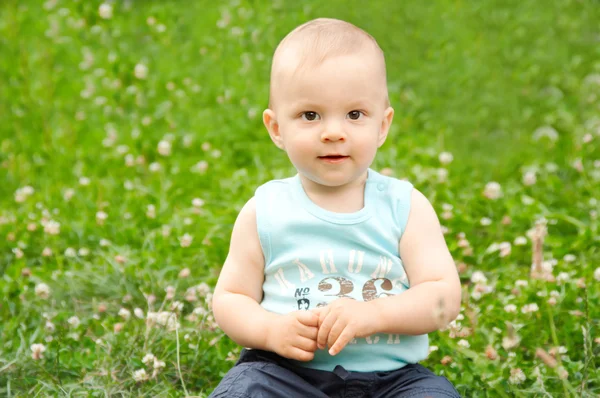 Yeşil çimenlerin üzerinde oturan bebek — Stok fotoğraf