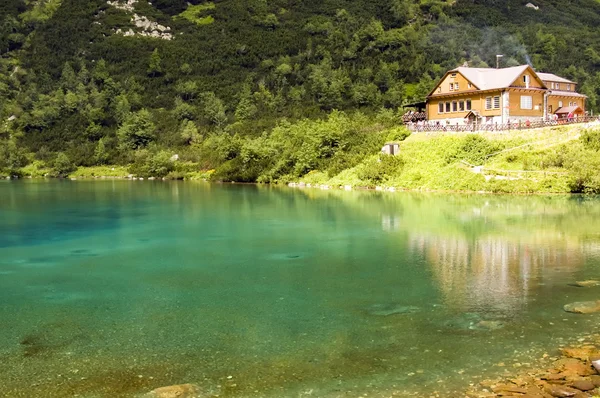 Chalet next to a green mountain lake — Stock Photo, Image
