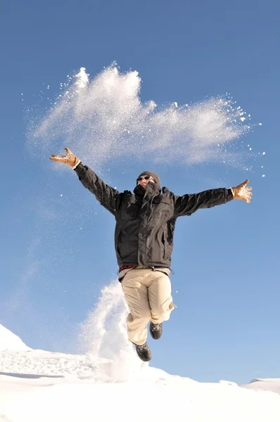 Чоловік стрибає на снігу Ліцензійні Стокові Зображення
