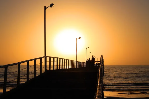 桟橋に沿って歩いて背後に夕日 — ストック写真