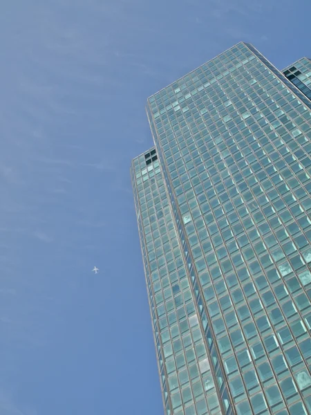 Green skyscraper and jet plane — Stock Photo, Image