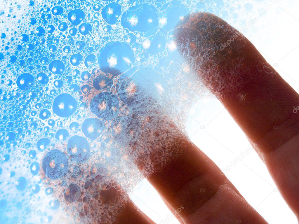 Fingers hold blue soap bubbles