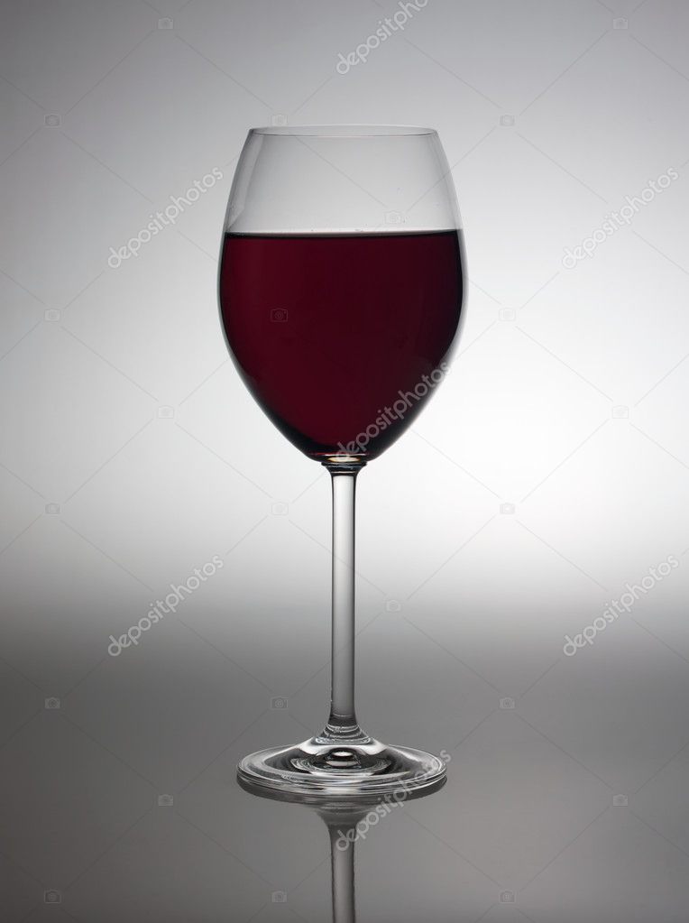 Glass with red wine in back light.