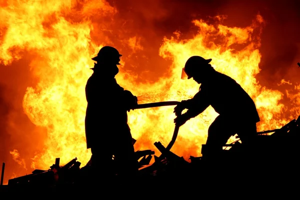 Zwei Feuerwehrleute und Flammen Stockbild