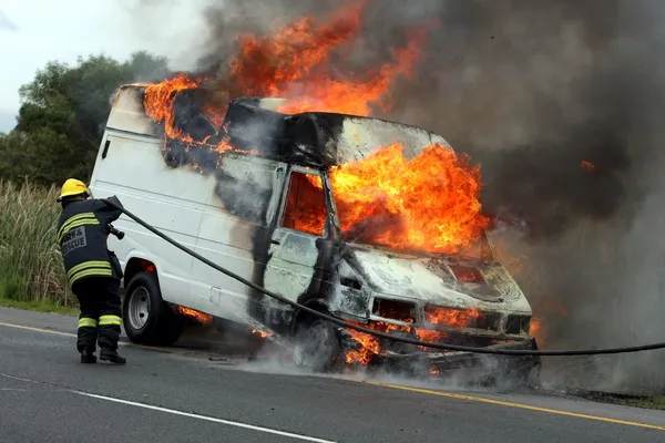Bombero y coche de motor en llamas — Foto de Stock