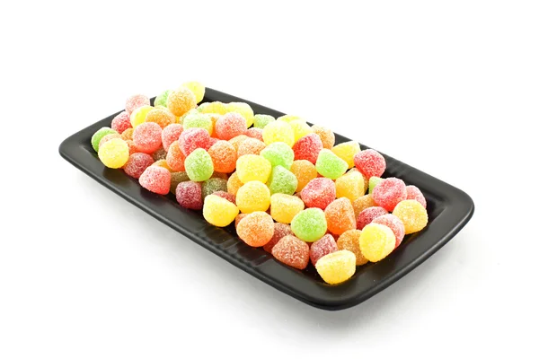 Яркие цветные сладости на черной тарелке — стоковое фото