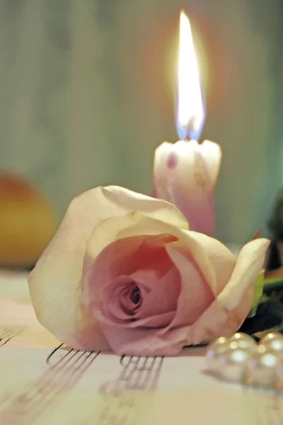 Candle and rose lieing on the music shee — Stock Photo, Image