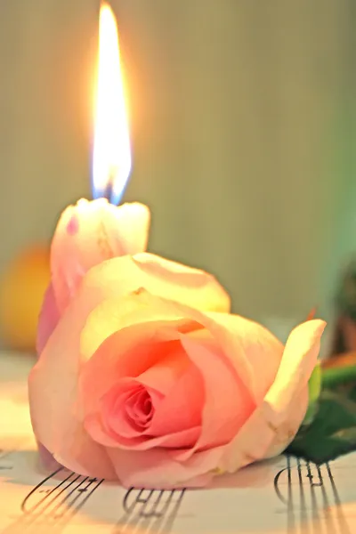 Candle and rose lieing on the music shee — Stock Photo, Image
