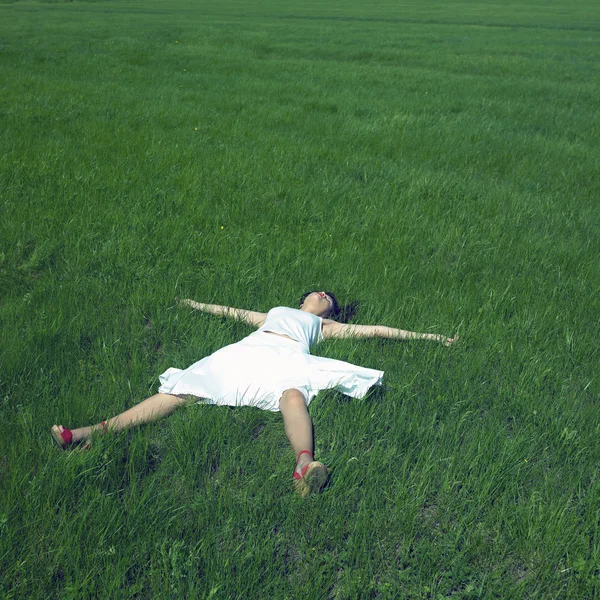 Zorgeloos meisje legt op een groen gras — Stockfoto