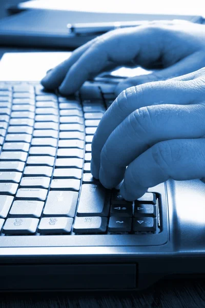 Handen te typen op het toetsenbord, op blauwe Toon — Stockfoto