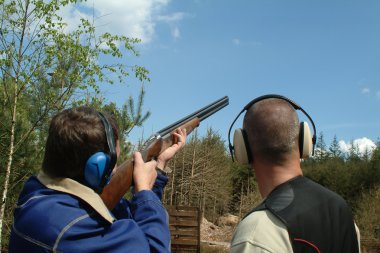 Man shooting clay pigeons being instruct clipart
