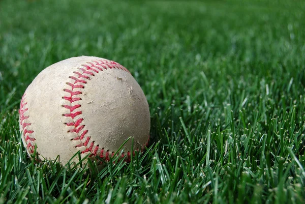 Бейсбол на траве Offcenter — стоковое фото