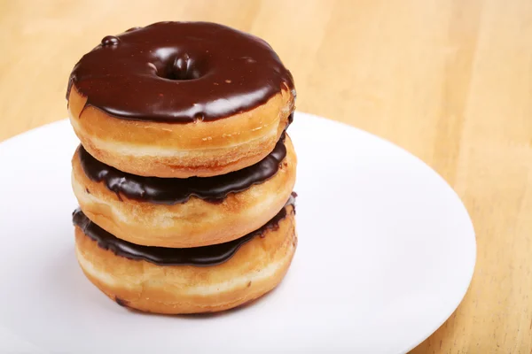 Three chocolate glazed donuts on plate — Stock Photo, Image