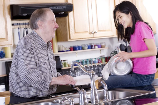 Старик и девочка моют посуду — стоковое фото