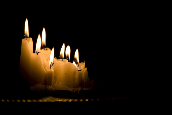 White candles burning in dark