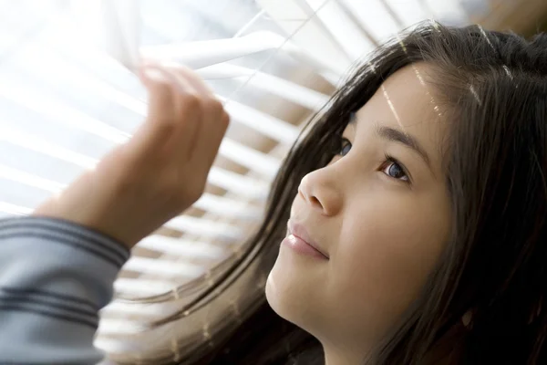 Meisje kijkt uit raam — Stockfoto