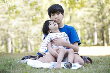 Young teen boy caring for brother clipart