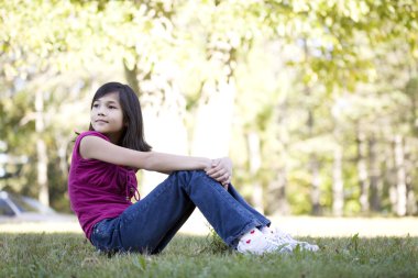 Little girl sitting on grass clipart