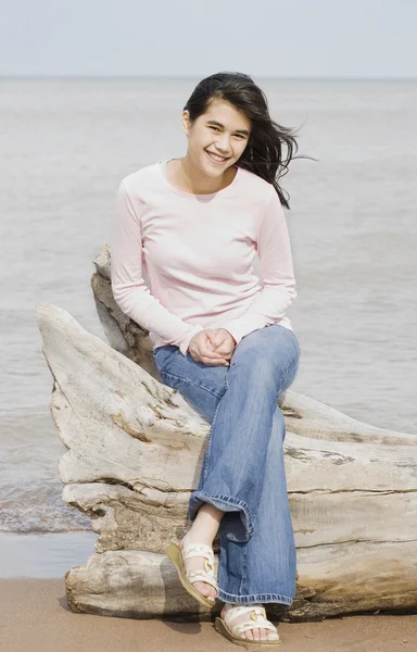 Adolescente chica sentado en caído registro por lago — Foto de Stock