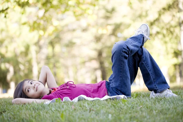 Küçük kız çimenlerde yatıyor. — Stok fotoğraf