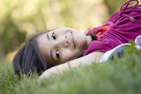Klein meisje liggend op gras — Stockfoto