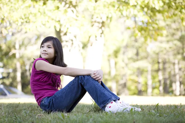 Petite fille assise sur l'herbe — Photo
