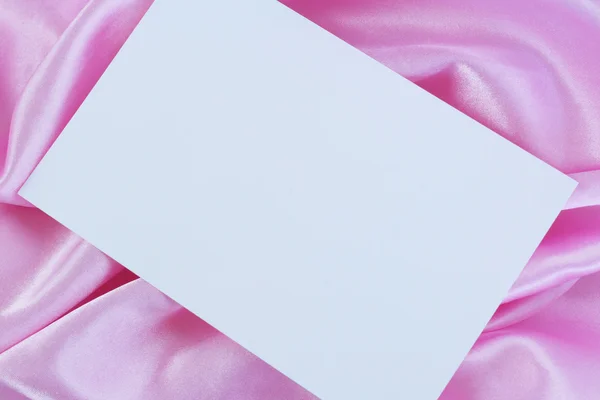 Tomt vitt kort på rosa satin — Stockfoto