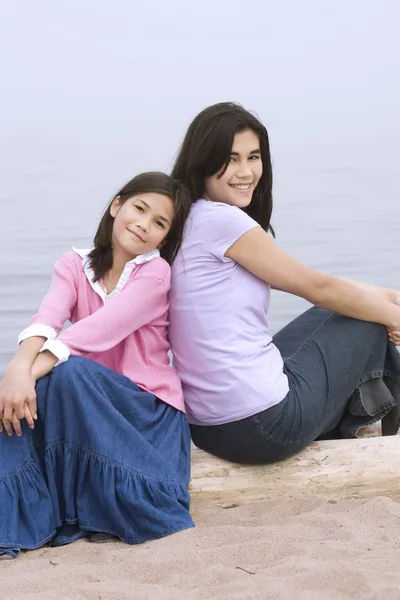 Deniz kenarında oturan iki kız kardeş — Stok fotoğraf