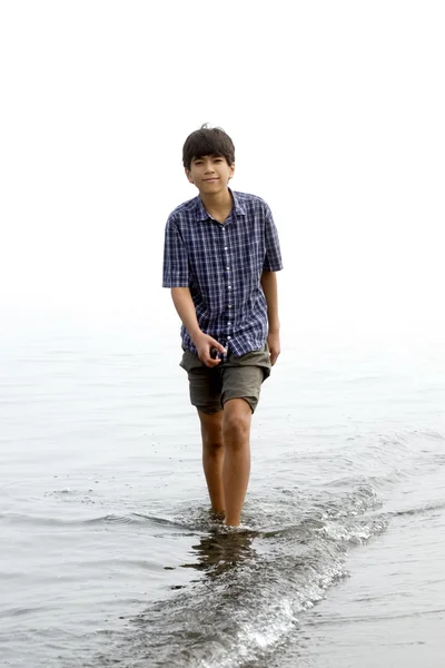 Young teen boy wading along beach — Stok fotoğraf